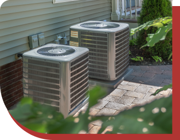 Two AC units outside on a brick patio against the wall of a house